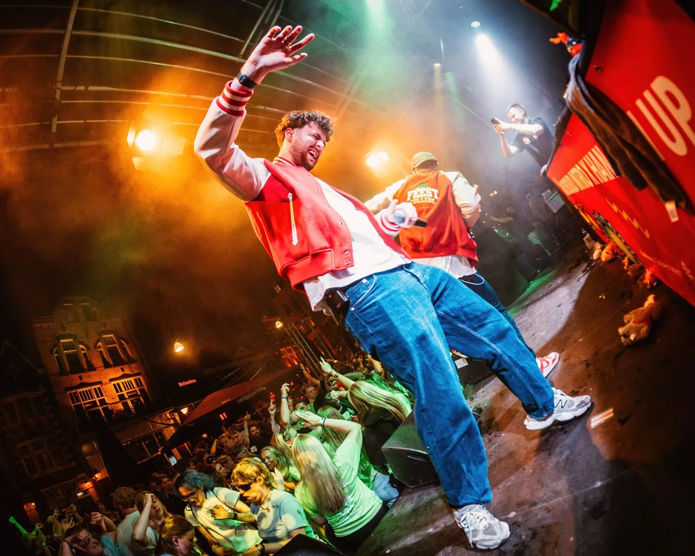 FeestCollege springt over het podium boven een volle straat met publiek