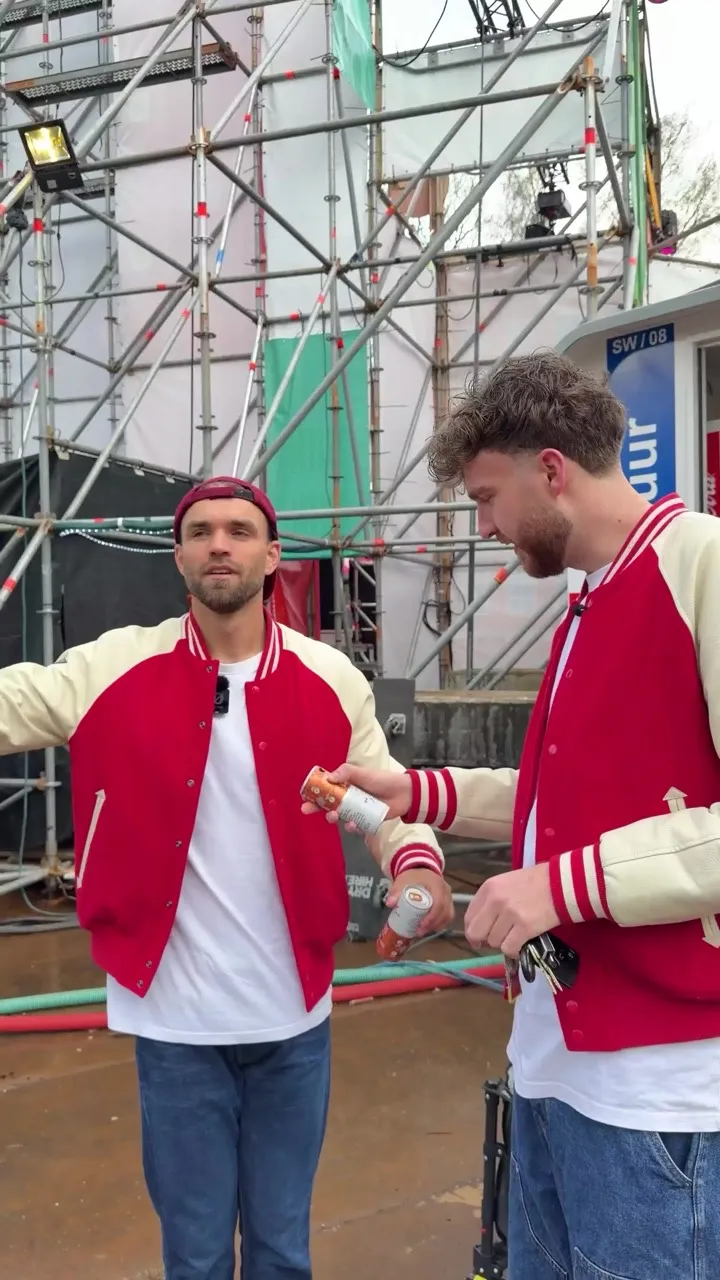 Levi en Samuel in rode FeestCollege-jacks met een blikje backstage bij Merlinpop